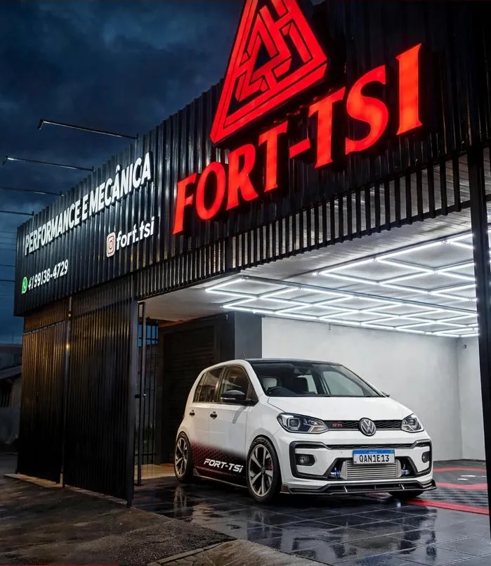Fachada da oficina Fort-TSI Performance e Mecânica em Pinhais, com um Volkswagen Up TSI preparado na entrada iluminada